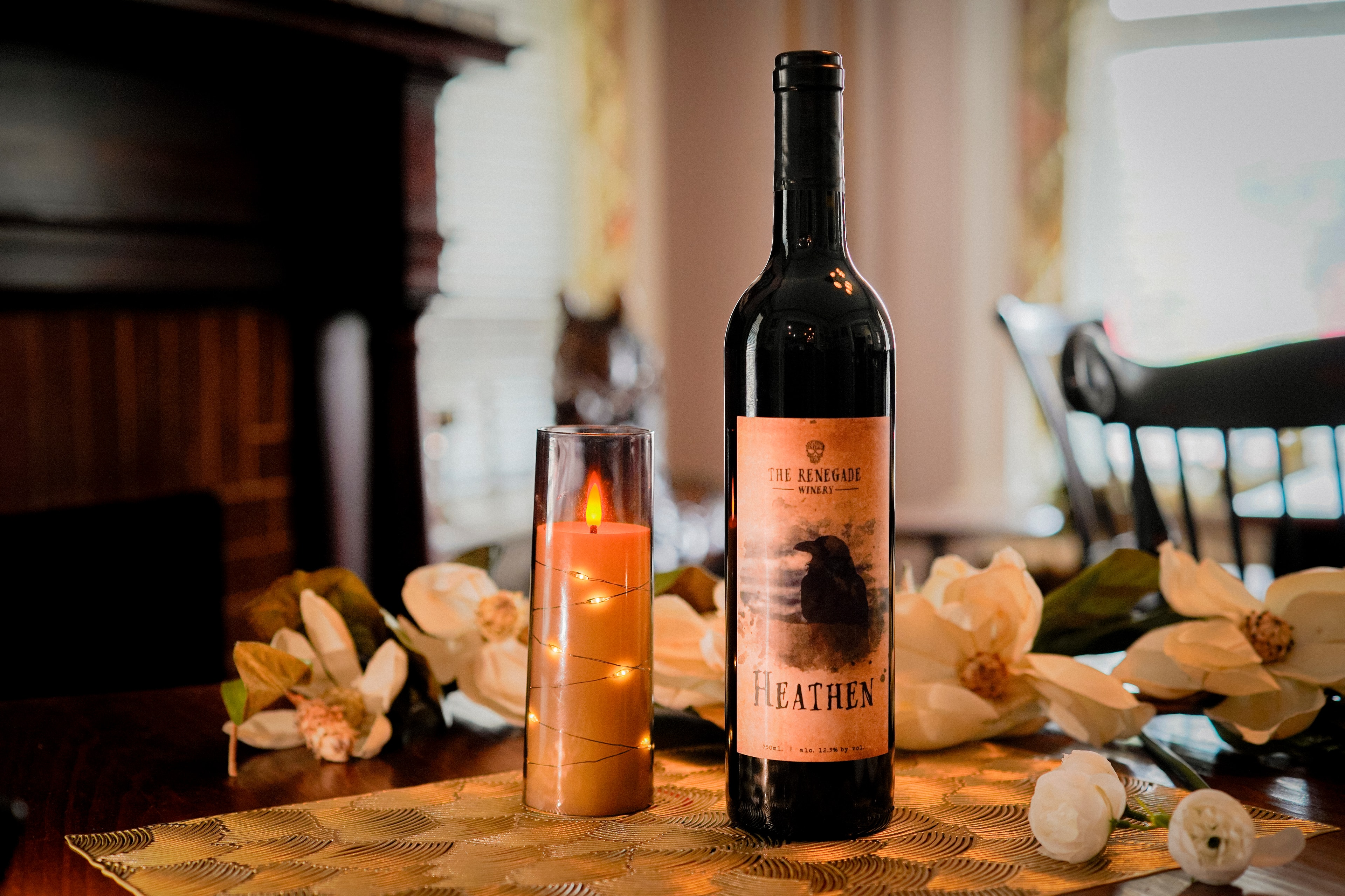 Renegade Winery Heathen red wine bottle with candle and magnolia flowers