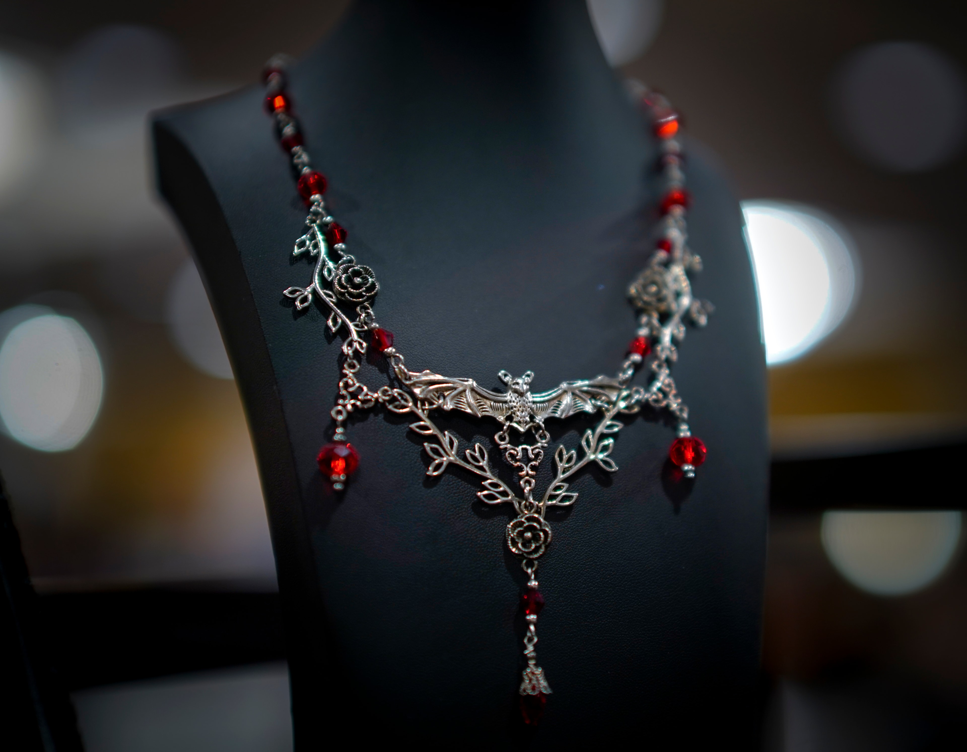 Ornate silver and red gemstone necklace on display bust