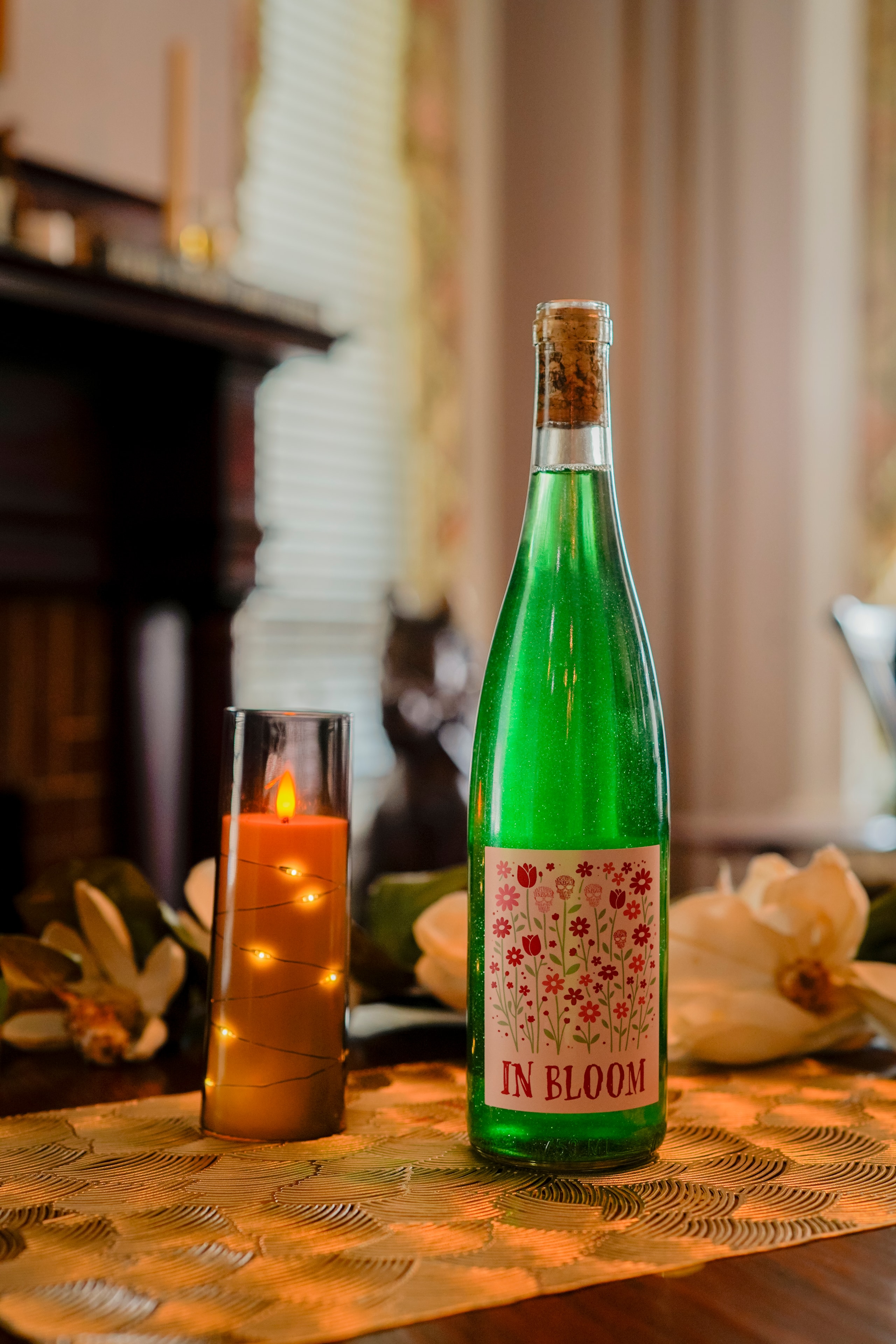 In Bloom green wine bottle with candle and magnolia flowers warm setting
